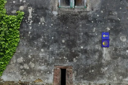 A stone building with the iconic Santiago de Compostela blue and yellow sign